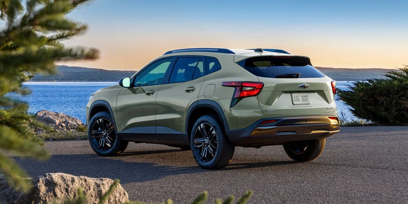 Light green Chevrolet Trax parked beside a lake at sunset.